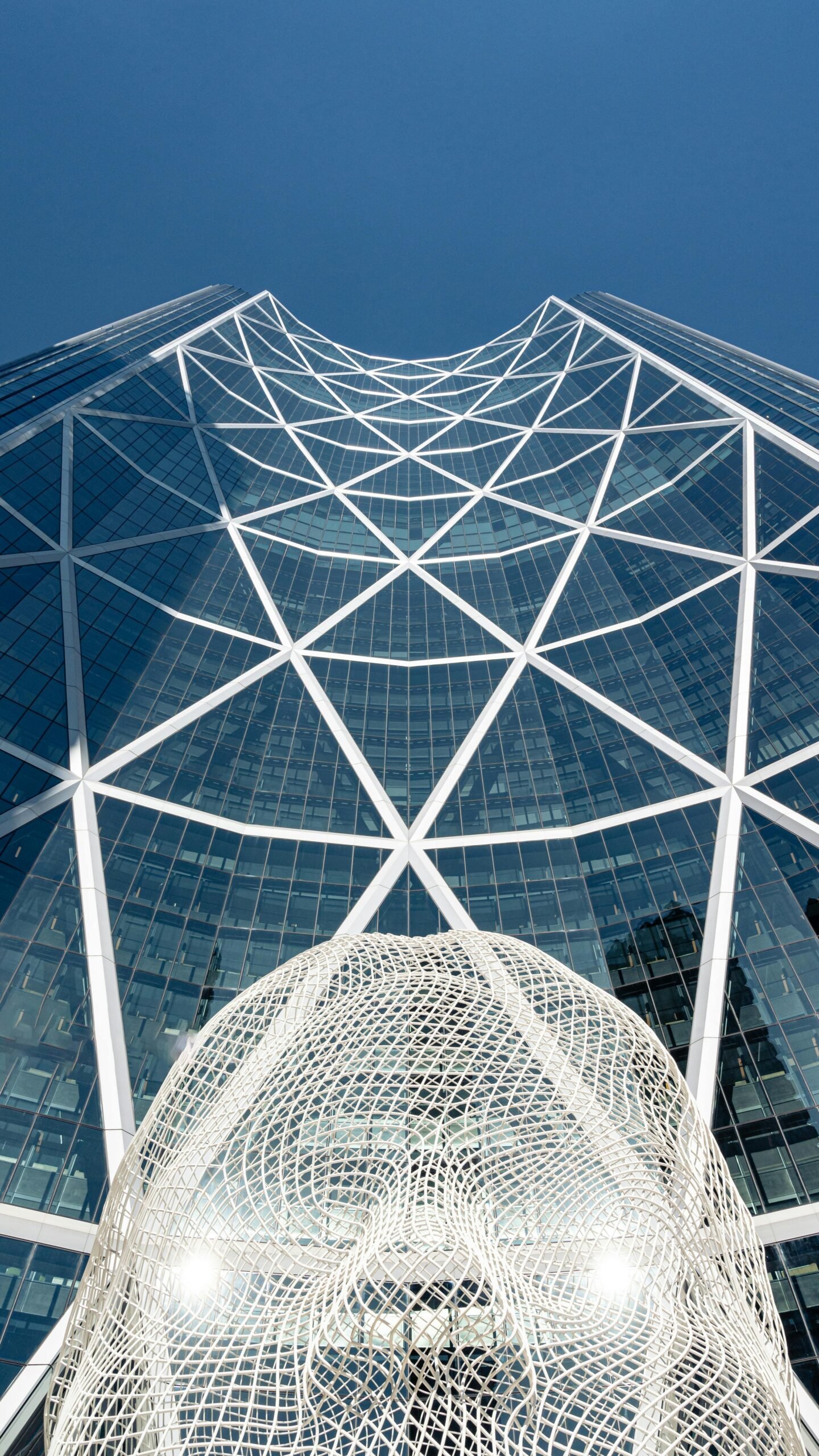Low angle view of The Bow skyscraper and a public art sculpture in Calgary, Alberta.